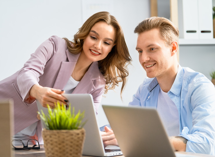 Two colleagues building an email campaign together on laptops